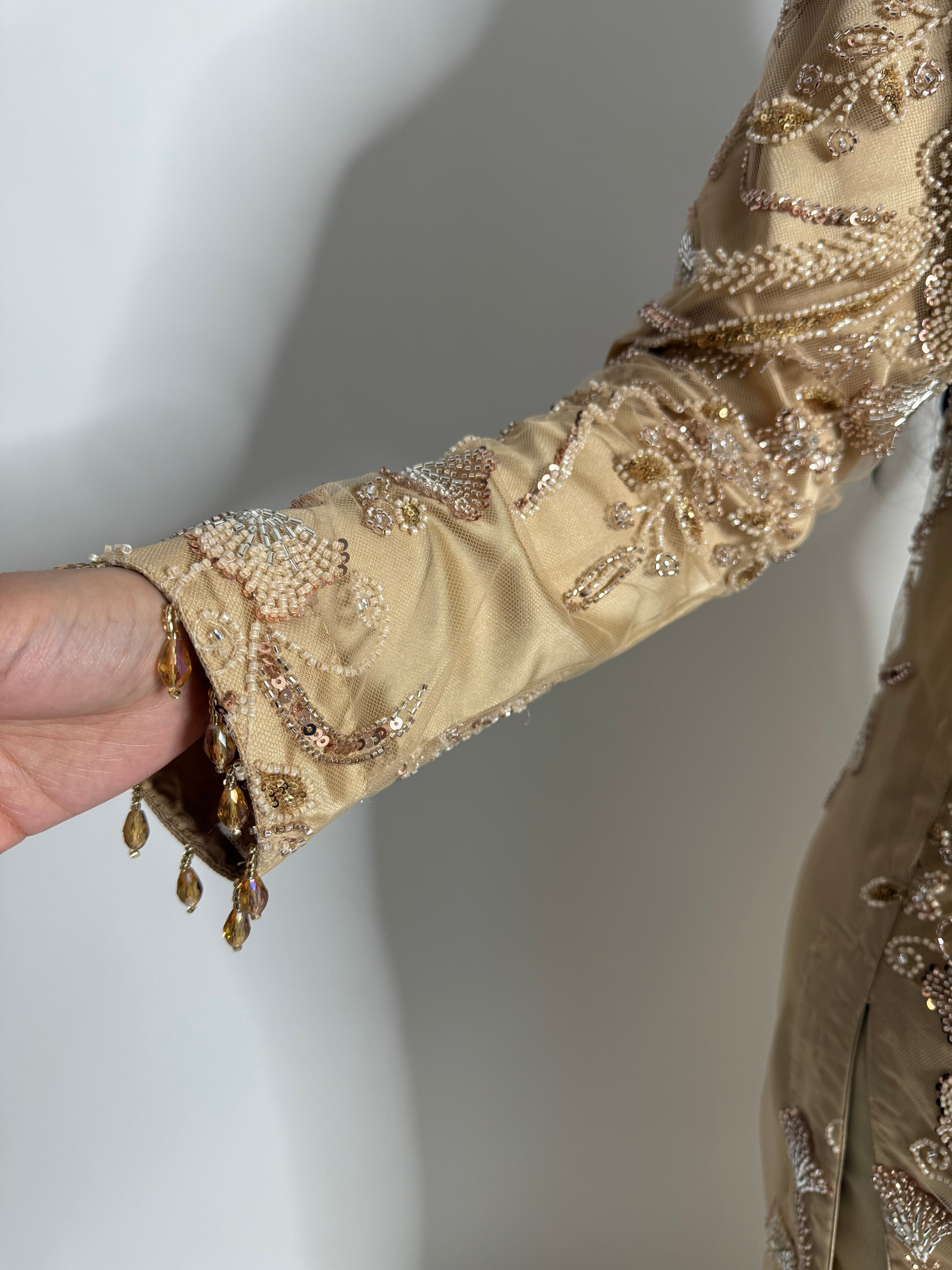 Gold embroidered sleeve with gold details on a plain background