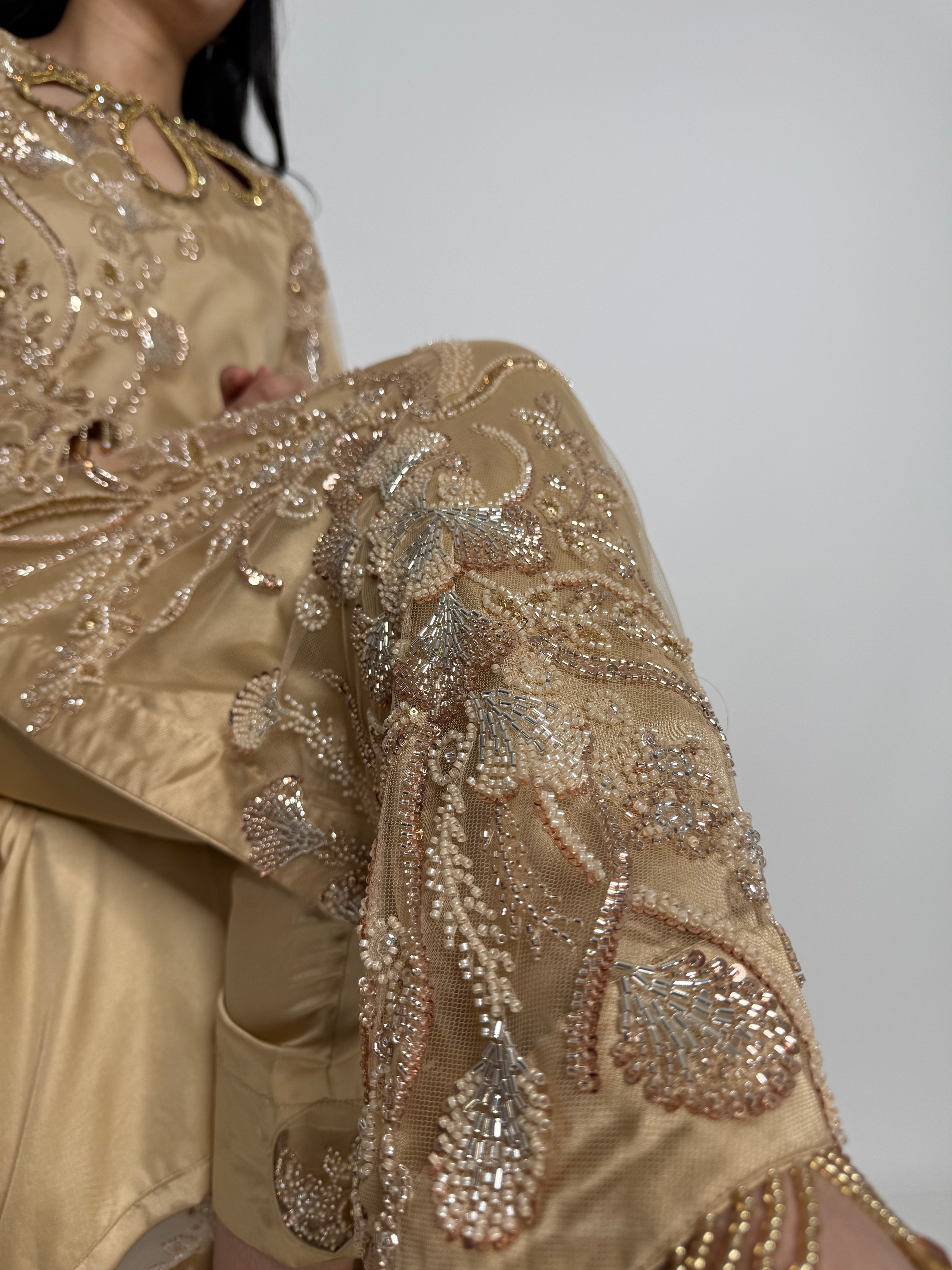 Close-up of a gold embroidered fabric with intricate patterns on a plain background