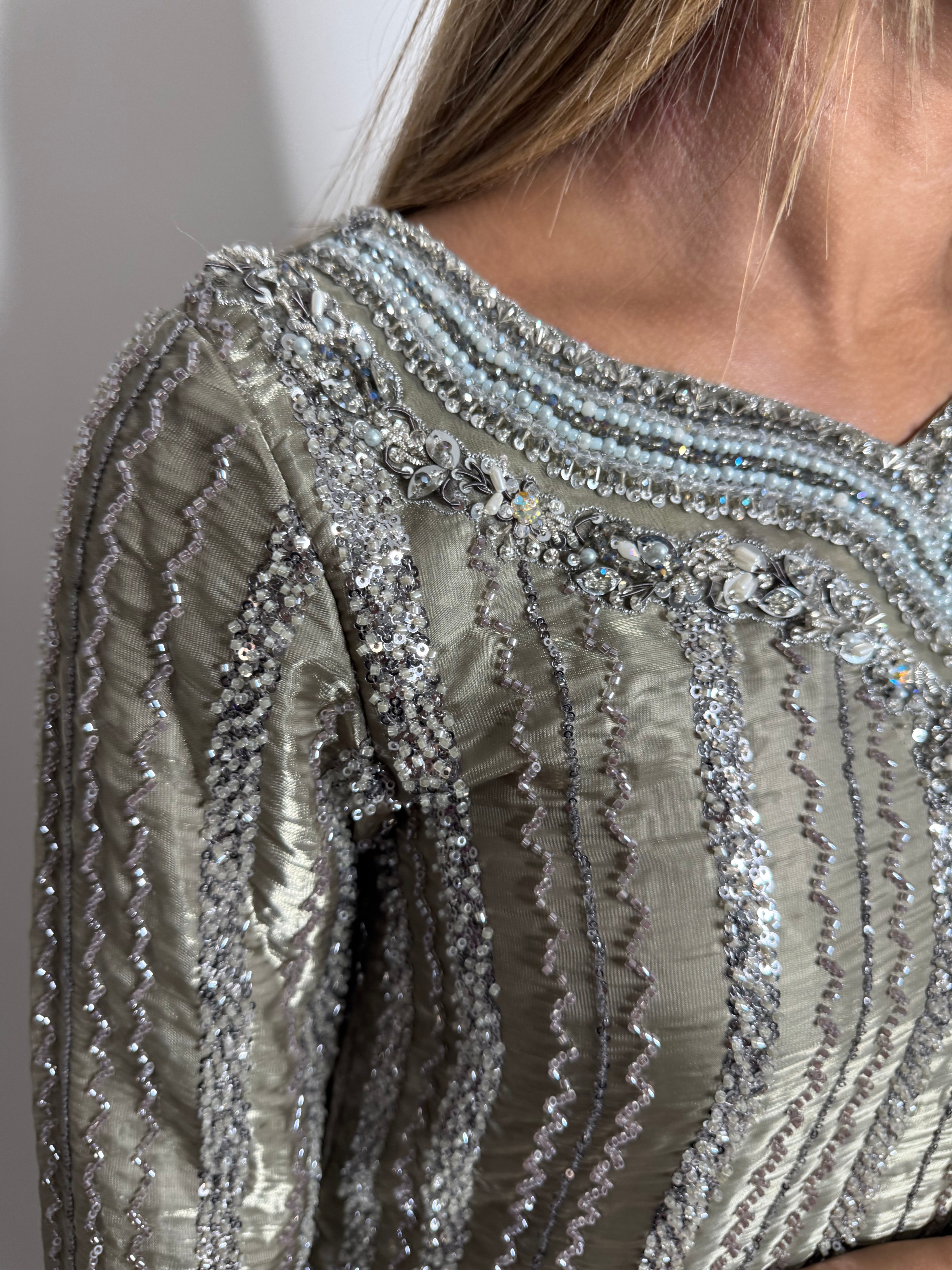 Close-up of silver embellishment on smoky sage formal outfit