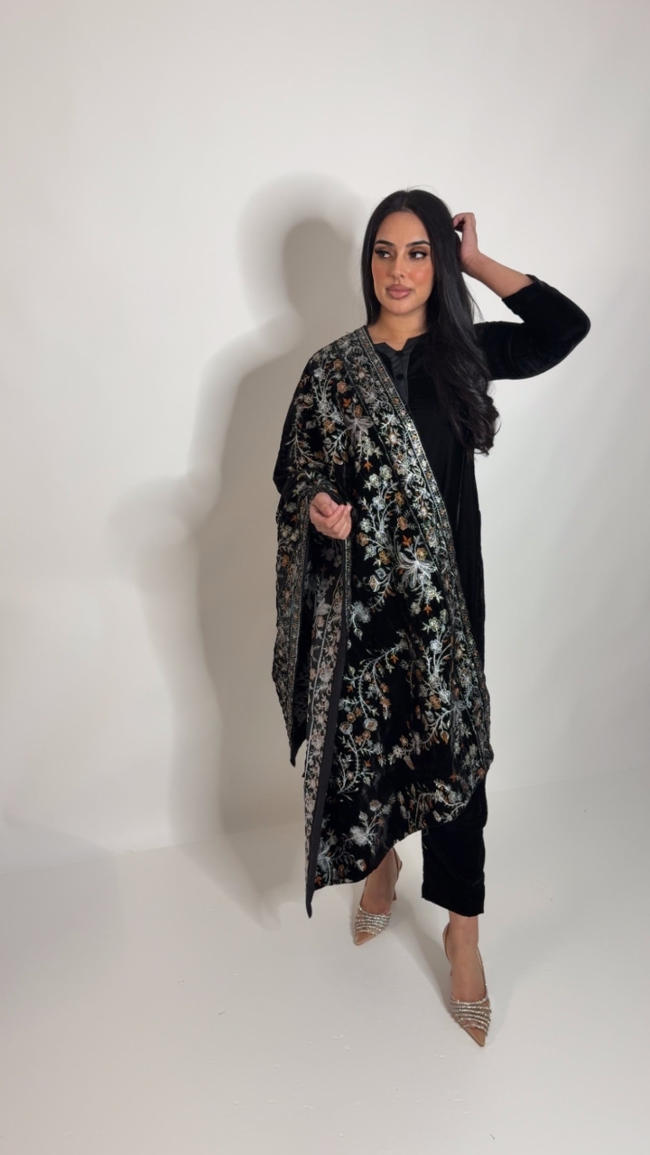 Model wearing a black velvet Pakistani outfit with a heavily embroidered silver thread shawl, styled for formal wear and wedding events.