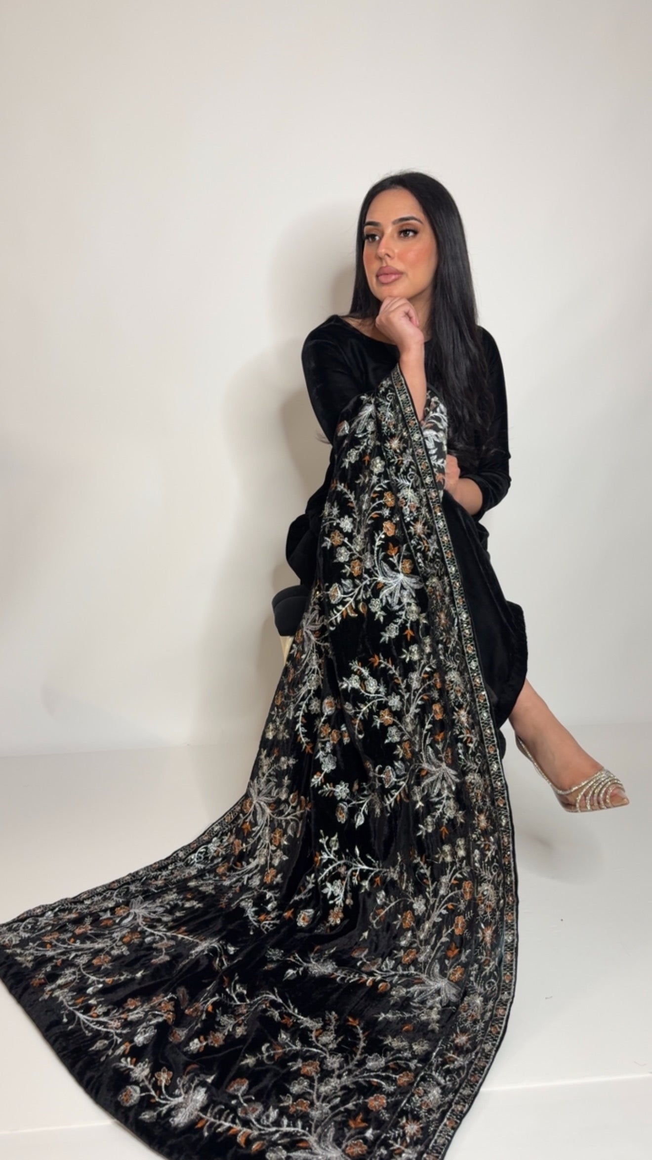 Model wearing a black velvet Pakistani outfit with a heavily embroidered silver thread shawl, styled for formal wear and wedding events.