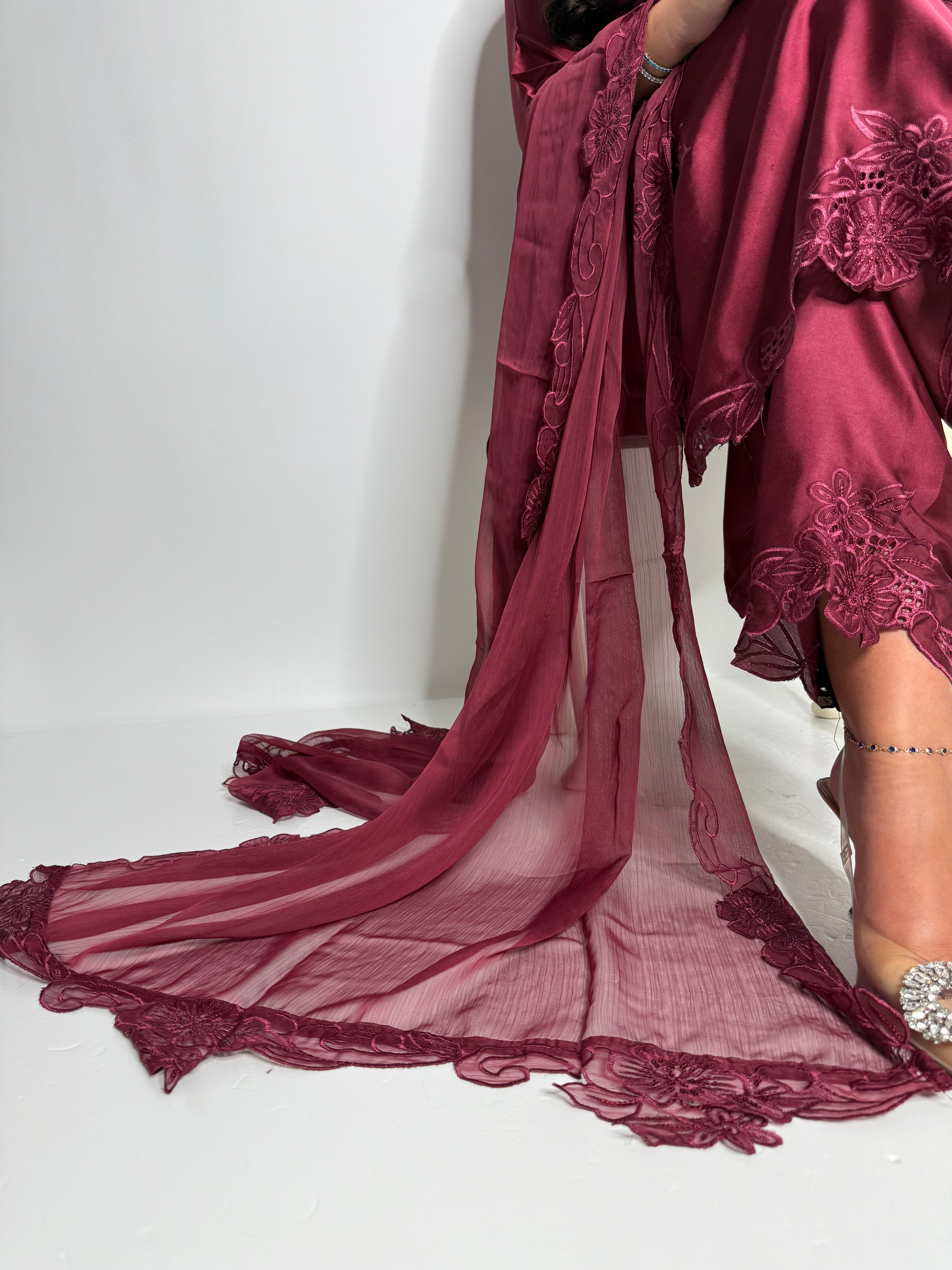 Close-up of wine satin fabric with tonal embroidery on shirt hemline