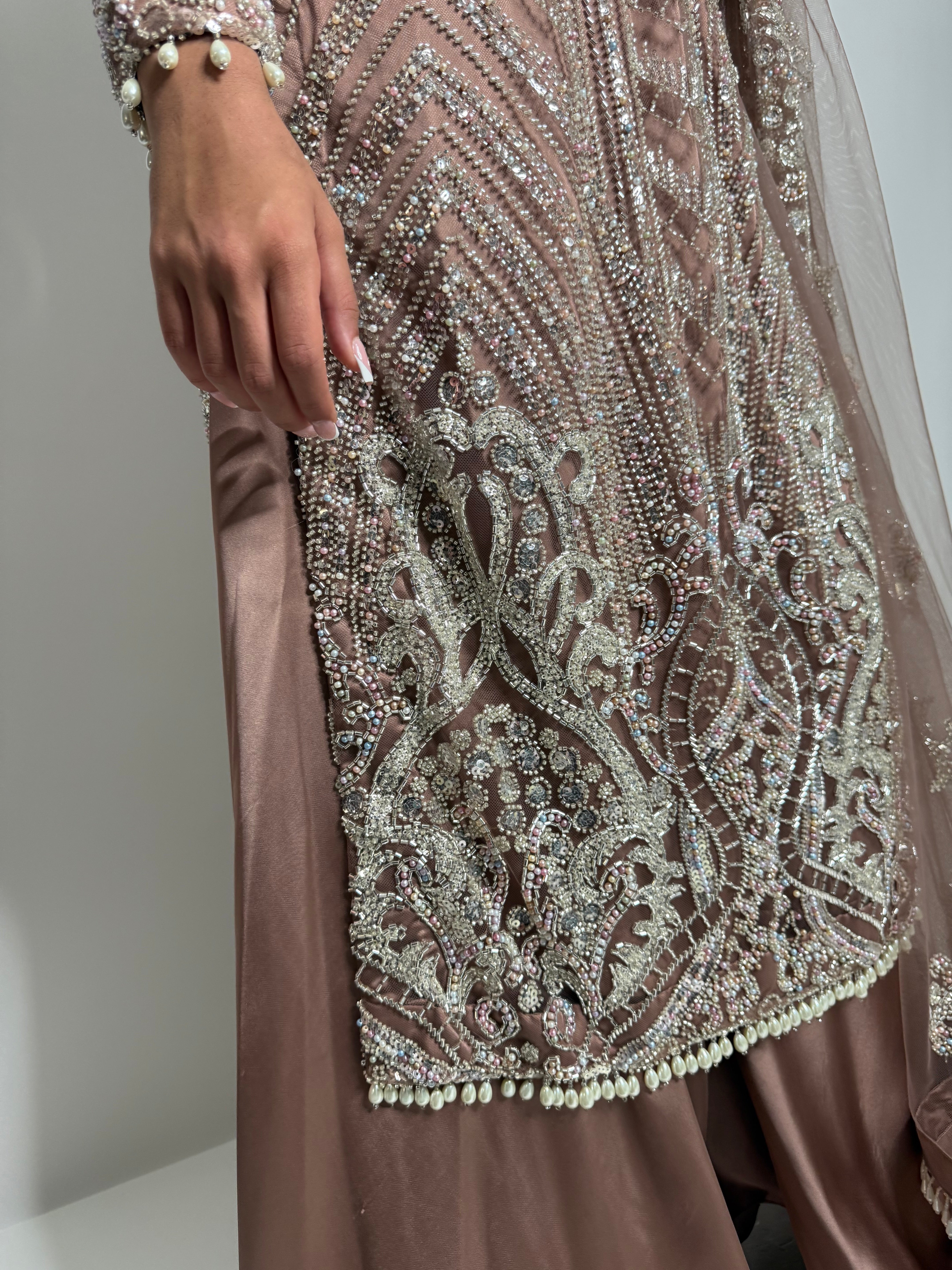 Close-up of silver embellishment and pearl edging on rose-gold blush shirt