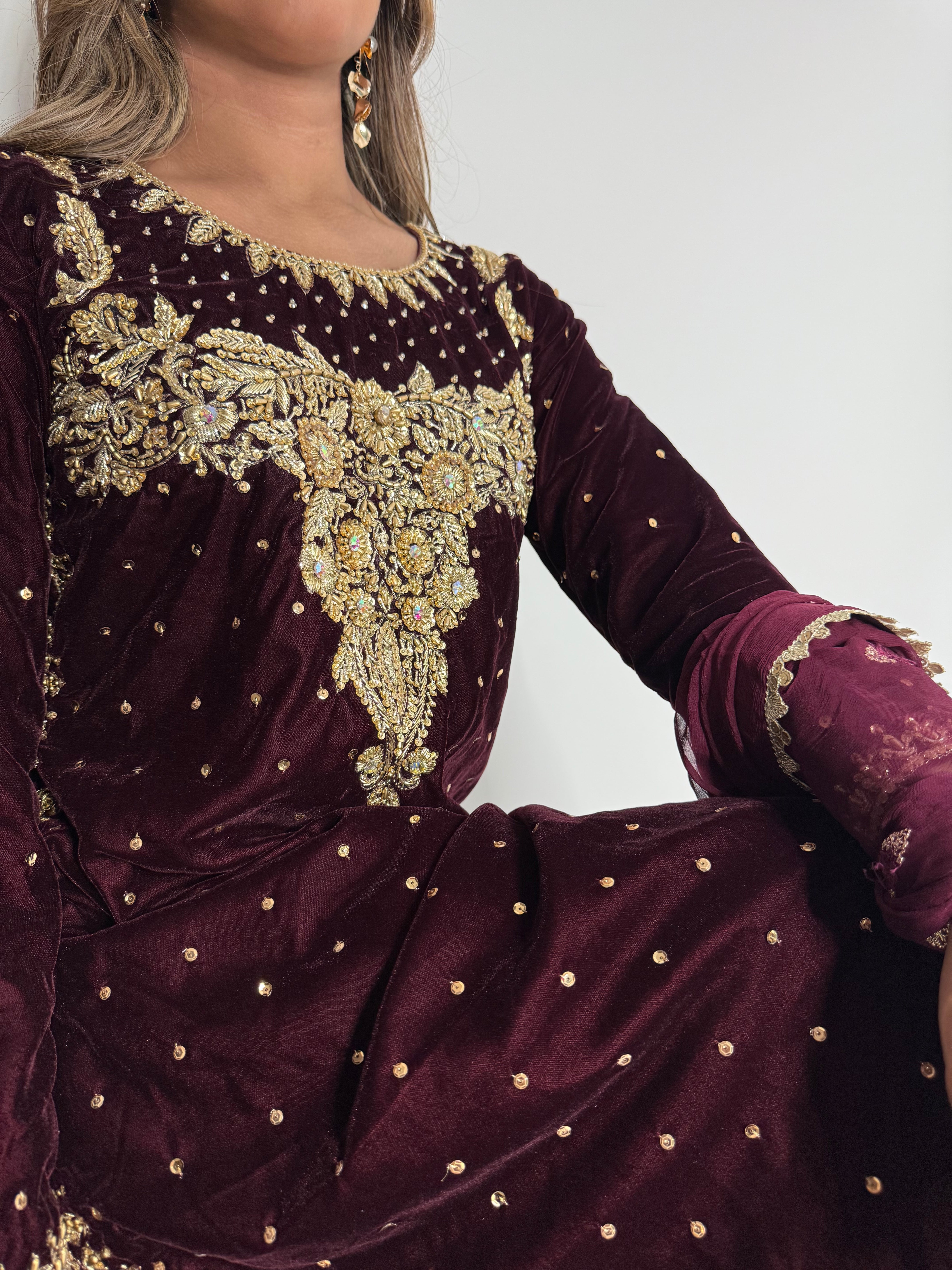 Close-up of golden embroidery on maroon velvet shirt.