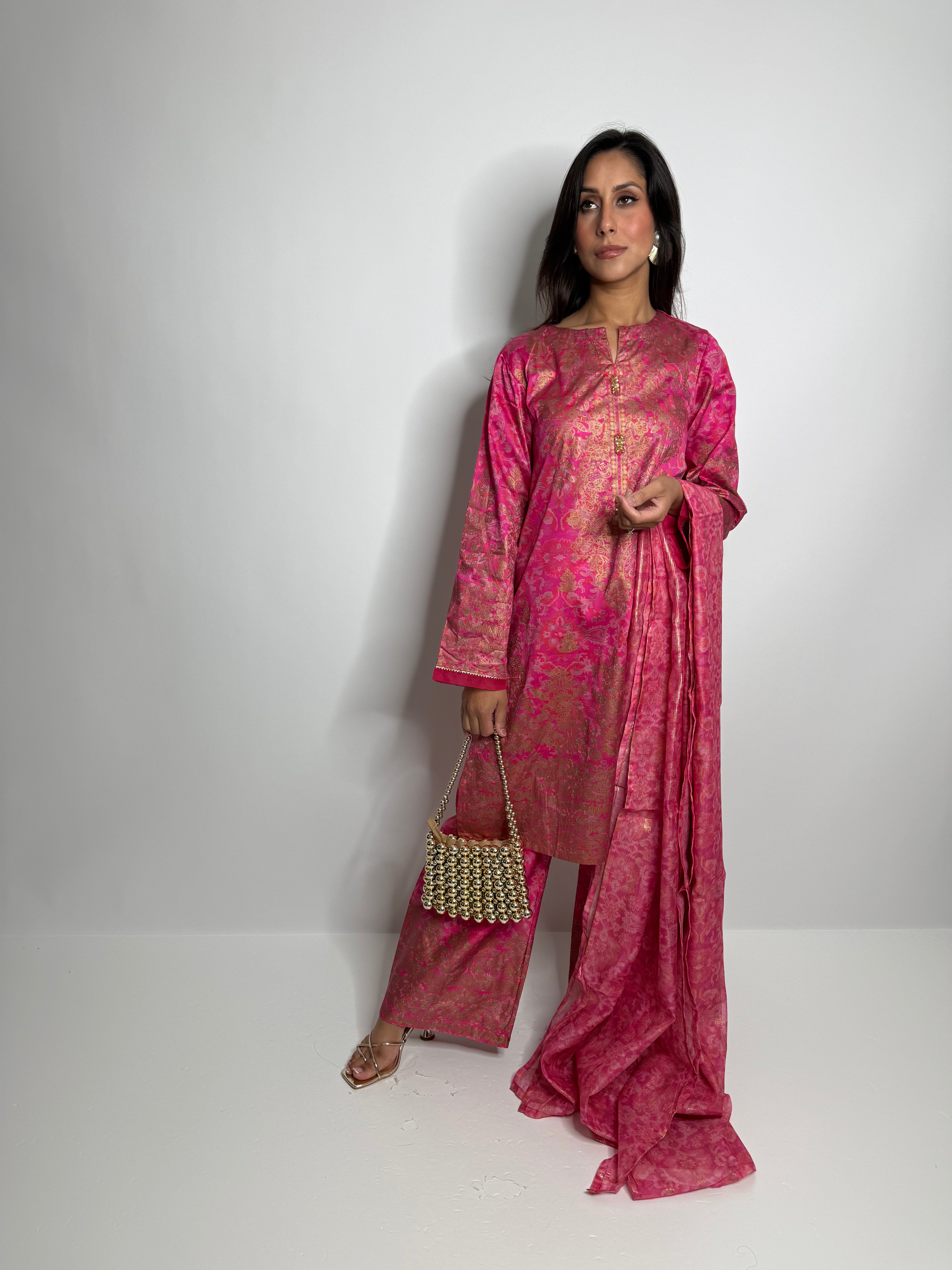 Model wearing fuchsia silk Limelight designer three-piece Pakistani outfit with kameez, trousers, and dupatta.