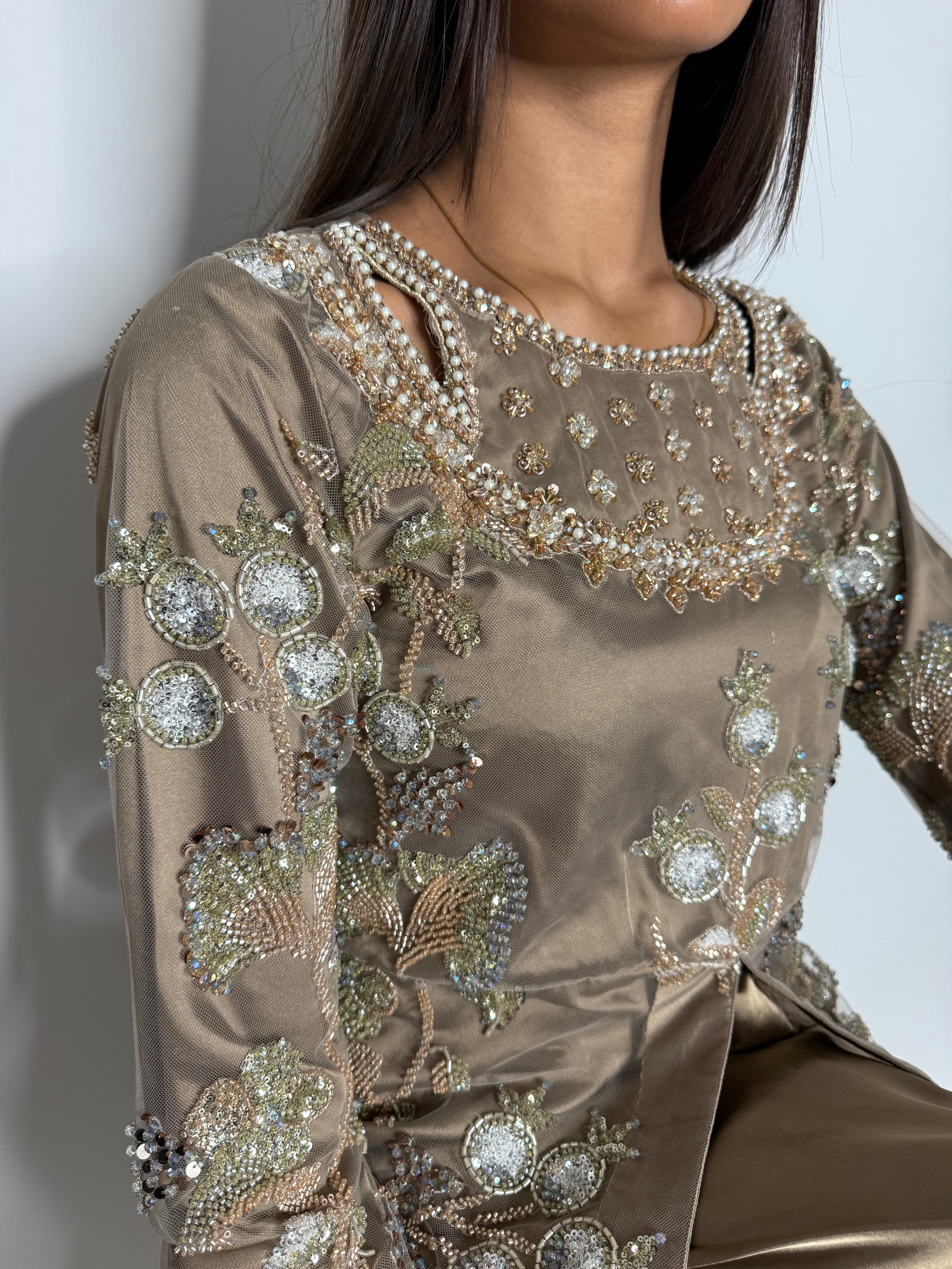 Close-up of Noorah cutdana hand-embellished detailing on taupe kameez with embroidery across front, back, and sleeves.
