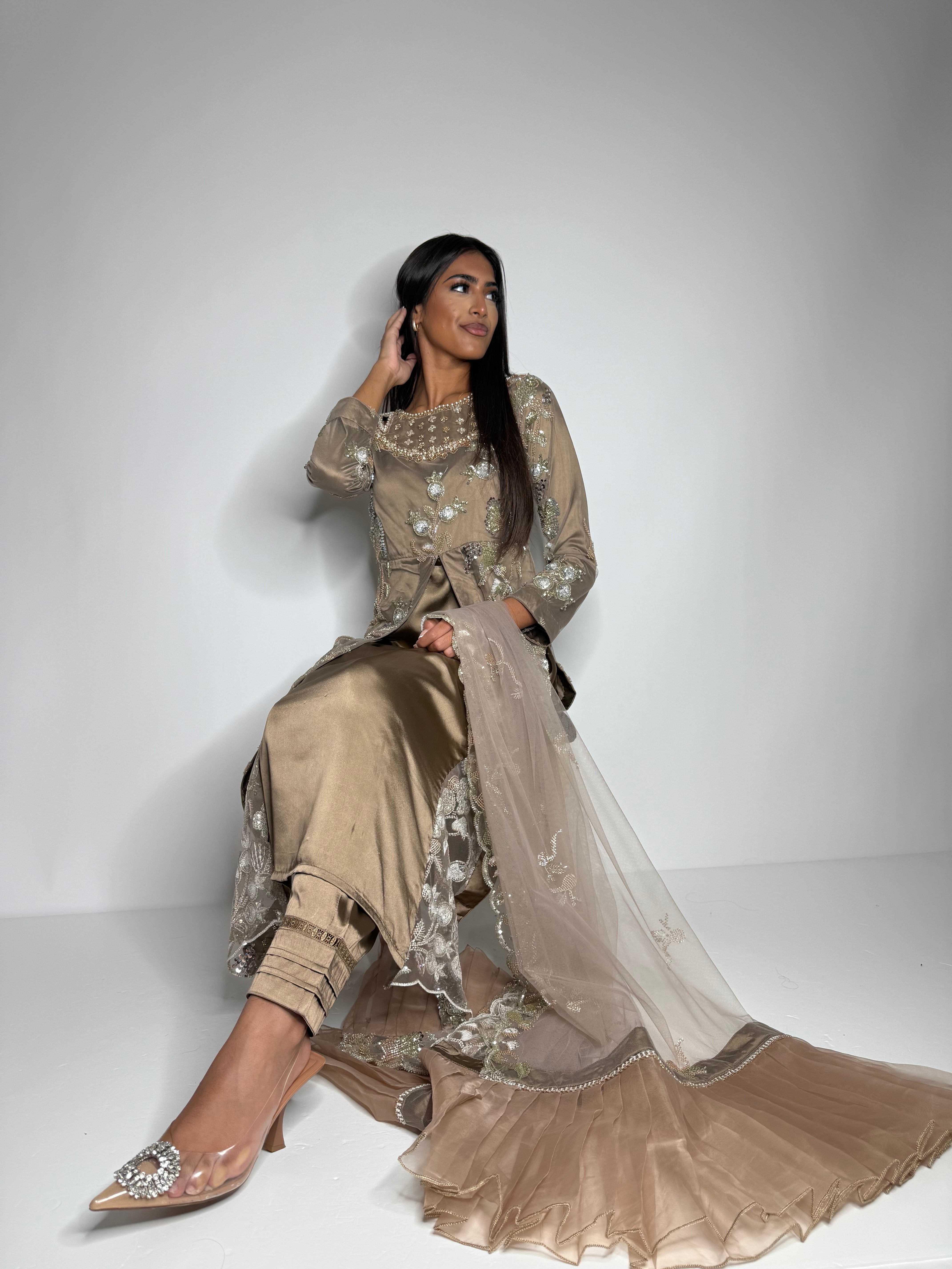 Model wearing Noorah taupe three-piece Pakistani outfit with cutdana embroidery, handwork, trousers, and net dupatta — perfect for weddings and festive occasions.
