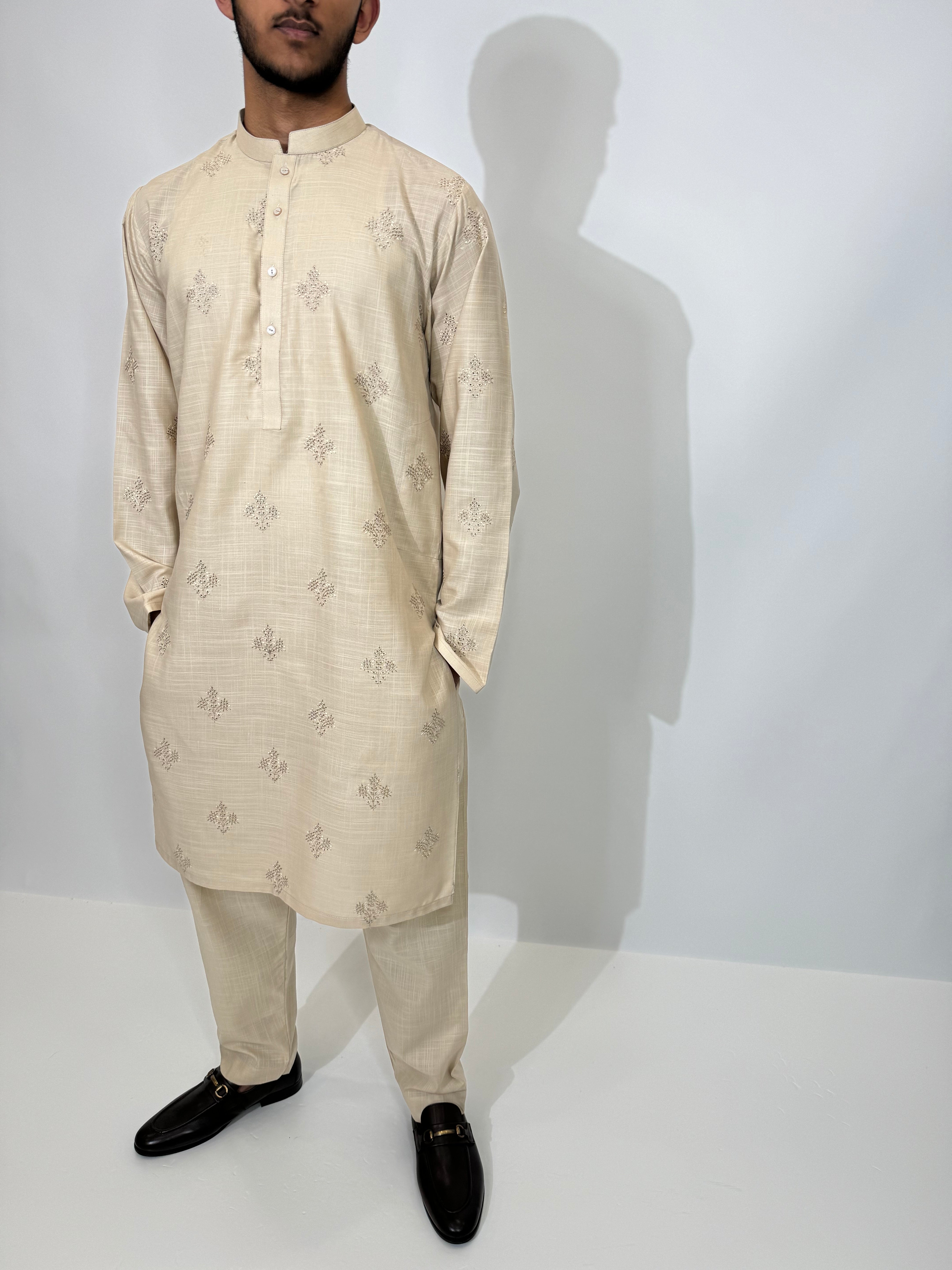 Model wearing a beige embroidered Pakistani men’s kurta with trousers — styled for Eid, weddings, or religious gatherings.