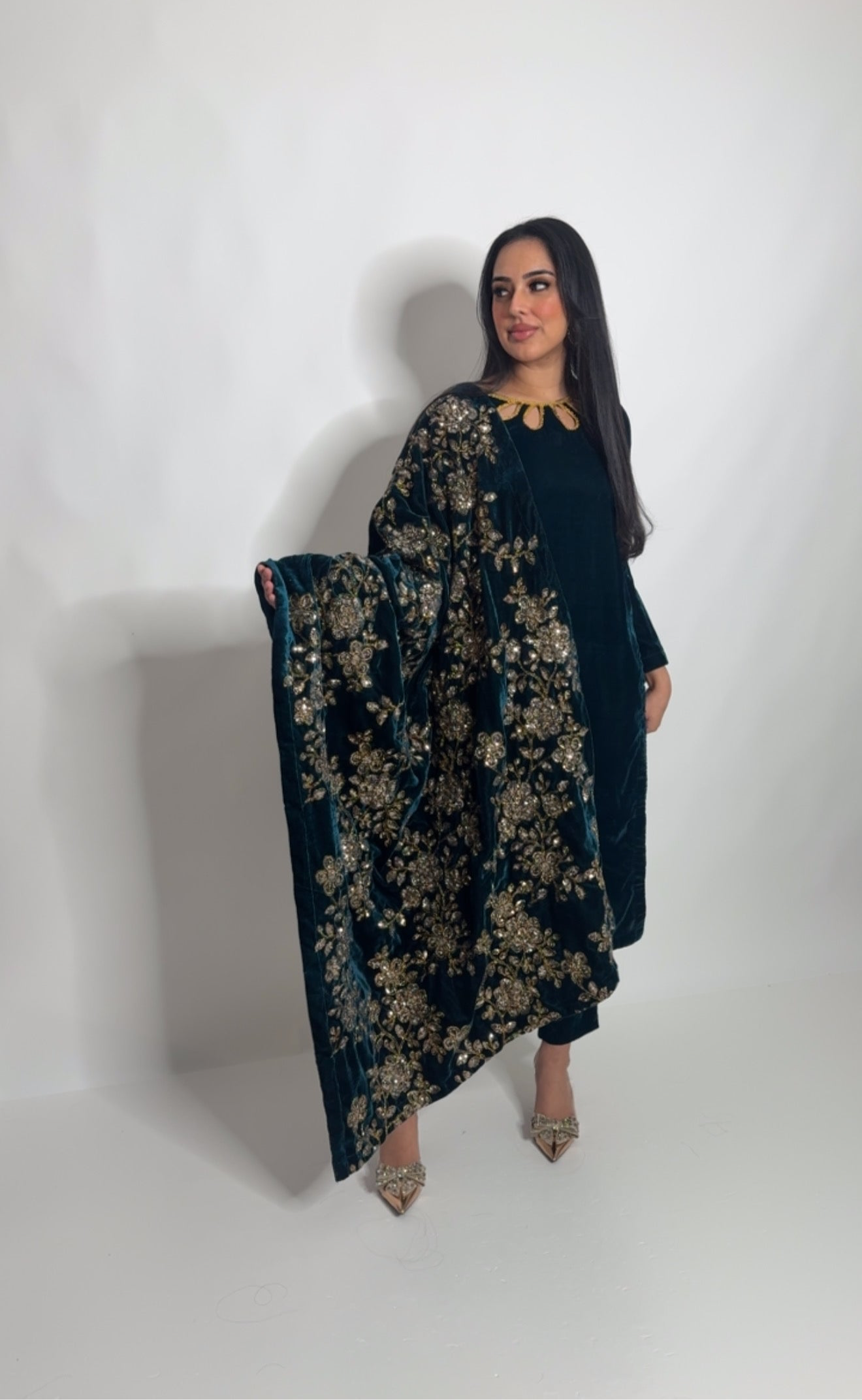 Model wearing a teal velvet Pakistani three-piece suit with an embroidered gold shawl, styled for winter daawats and weddings.